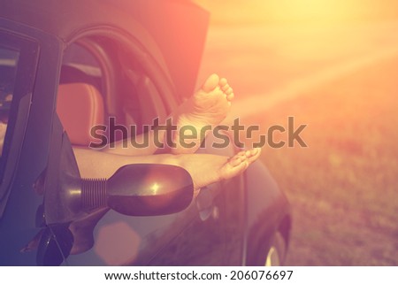 Vintage photo of woman\'s legs in high heel shoes out of car windows in summer sunset