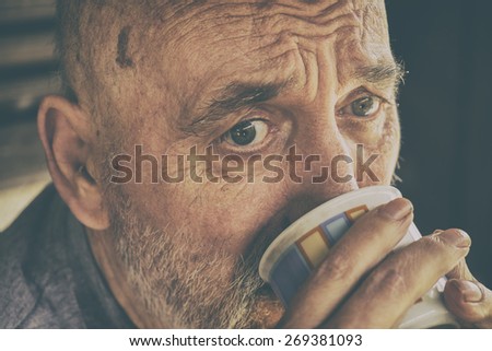 Very old senior man drinking coffee / tea. Analog effected photo.