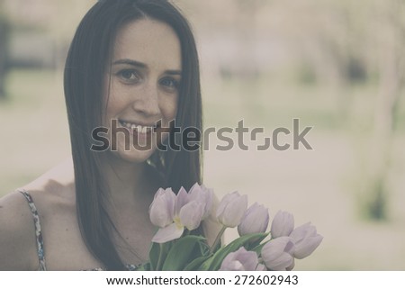 Beautiful woman with bouquet of tulip flowers. Analog effected photo.