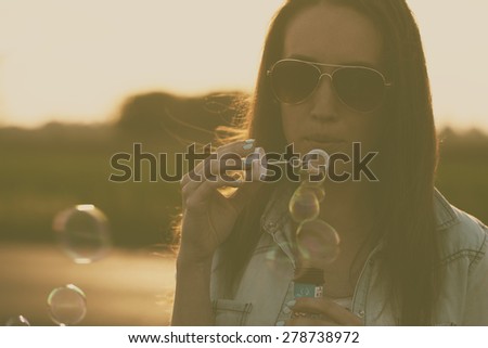 Vintage photo of woman blowing soap bubbles in summer sunset
