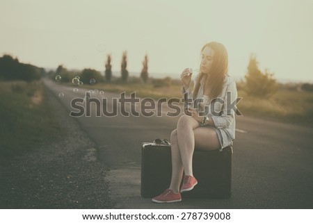 Traveler woman blowing soap bubbles in summer sunset