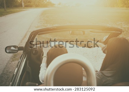 Two traveler woman on the road in cabrio car with map