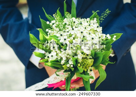 wedding bouquet with white flowers in the hands of the groom