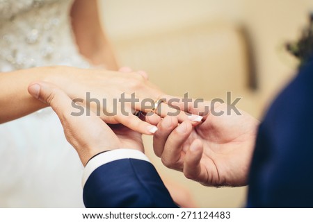 Man placing an engagement ring on his girlfriend\'s ring finger