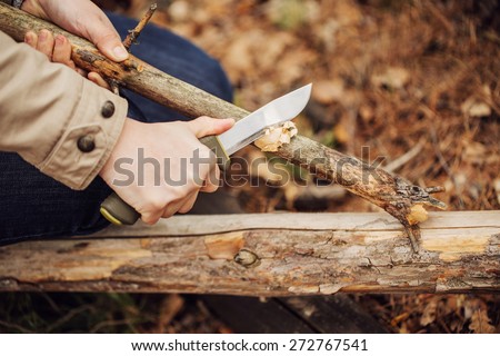 Girl cuts a stick a knife in the woods