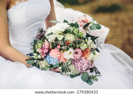 unusual wedding bouquet with different flowers in the bride\'s hands