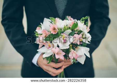 bridal bouquet of white orchids in the hands of the groom, close-up