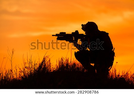 Silhouette of military soldier or officer with weapons at sunset. shot, holding gun, colorful sky, background