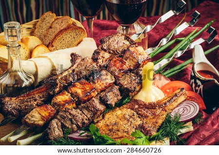 fried grilled meat with vegetables, sauce and wine in glass glasses