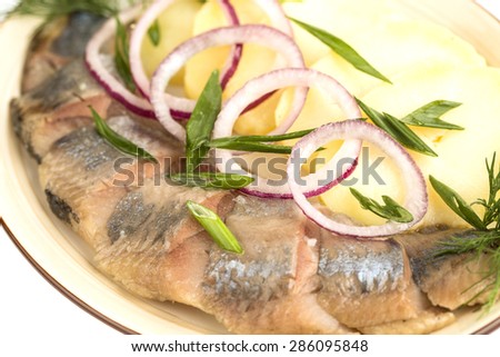 Plate of herring fish fillets with potato, dill and red onion rings