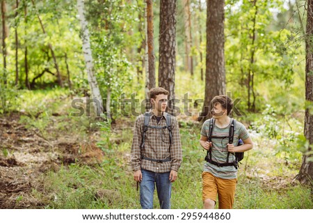 two young tourist talk and go through the woods with backpacks