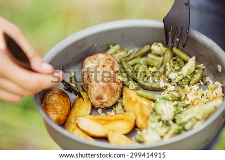 young man eating meat with rice and vegetables in the forest in sunny day