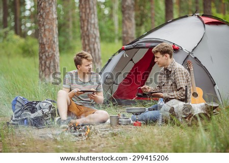 Two young men are heated in a fire and cook out on a summer camp