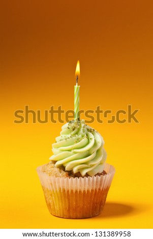 cupcake with candle isolated on orange background