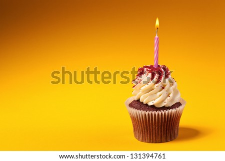 chocolate cupcake with candle isolated on orange background with copyspace
