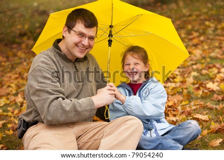 happy dad and daughter under yellow umbrella (focus on girl)