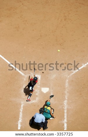 An aerial view of a woman\'s softball game showing the batter, catcher and the home plate umpire.