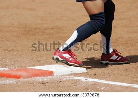 The cleats of a softball player on the plate about to run during a game.