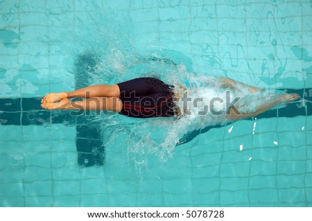 An aerial view of a female swimmer just off the starting blocks