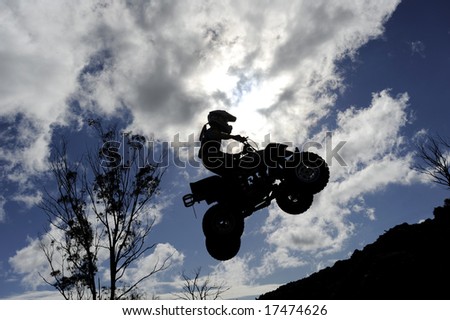 stock photo : A silhouette of a quad bike (ATV) jumping through a cloudy