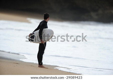 A male surfer checks the waves before heading out into the ocean.
