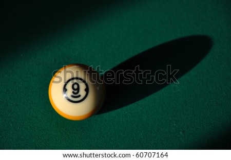 A lone nine ball casts a long shadow on the green pool table