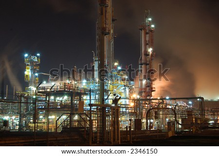 Petroleum refinery by night with billowing clouds of orange smoke