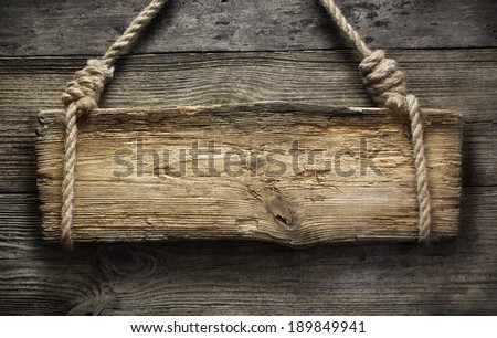 Wooden sign hanging on a rope on wooden background
