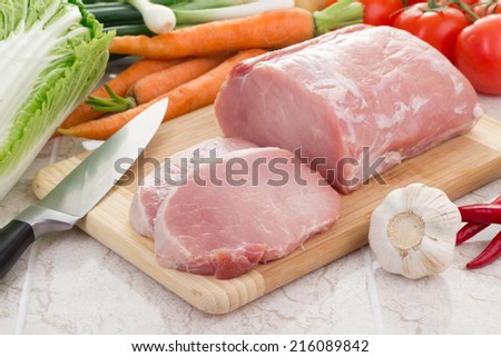 Fresh meat and vegetables on kitchen board