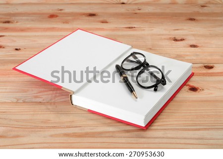 red book with glasses and pen on the wooden