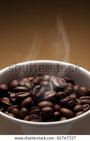 White cup full of fresh roasted coffee beans.