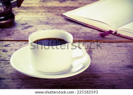 Cup of black coffee with a book on a wooden table