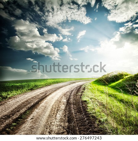 Turning highway into the field for hills under dramatic sky