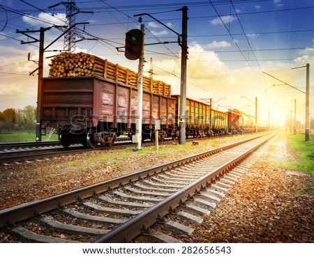 Railway with freight train receding into the distance to the sun