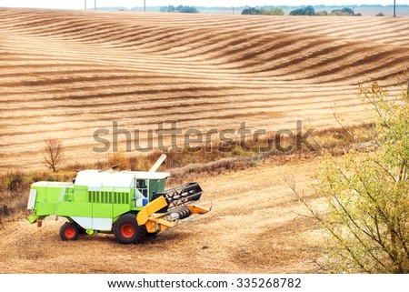Wavy sloping field with combine in the corner