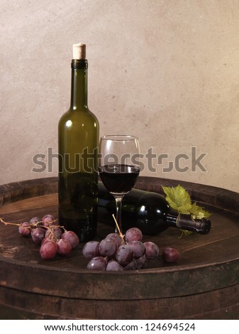 still life with red wine, bottle, glass and old barrel