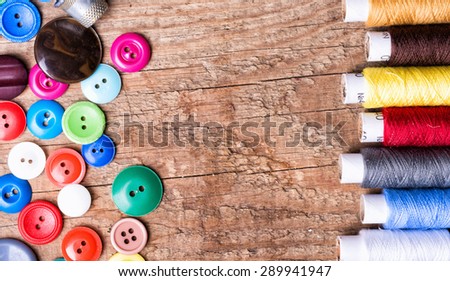 Spools of threads and buttons on old wooden table