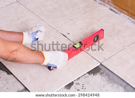 Home renovation, worker leveling tiles with level tool