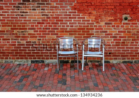Red Brick Wall and Two Metal Chairs