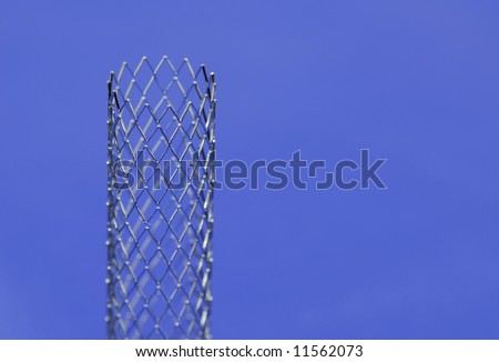 This is a stent in front of blue background. A stent is a small mesh tube that’s used to treat narrowed or weakened arteries in the body.
