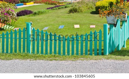 Green picket fence with road, green garden and flower