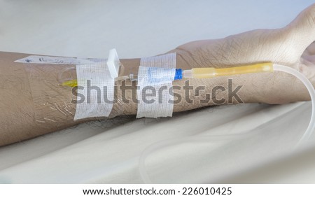 IV needle on patient arm for medicine injection after surgery