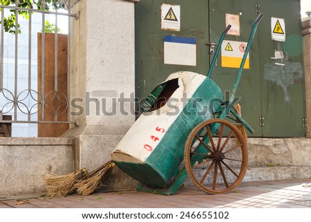 Broom and cart at sidewalk for cleaner in the city