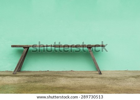 Old wooden bench and green on concrete wall