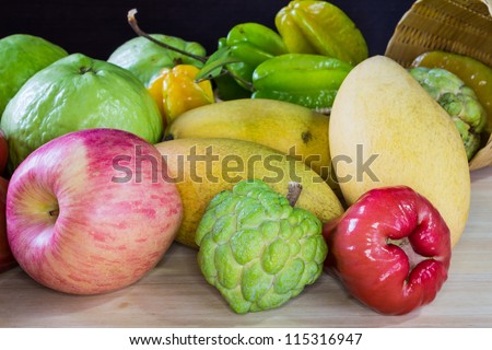 Tropical fruits on wooden table, including apple, rose apple (champoo), guava, mango, sugar apple and star fruit