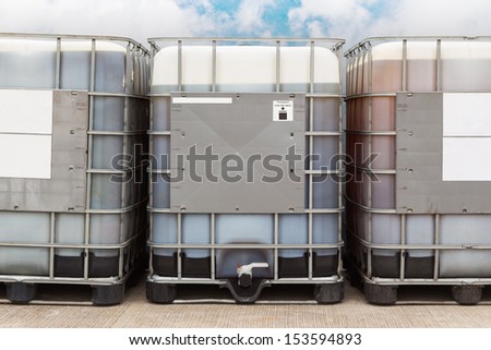 Bulk plastic oil containers with metallic cage in storage area
