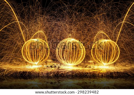 Fire balls of spinning hot steel wool, with water reflection