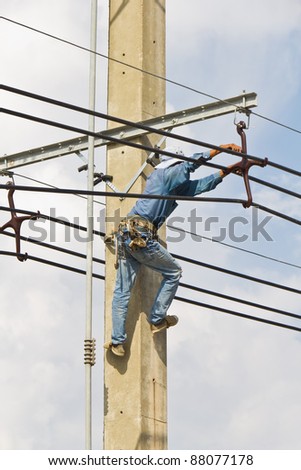 An electrical worker, on concrete pole, performs transmission lines repairing