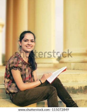 Happy ethnic Indian / Asian college student studying on campus