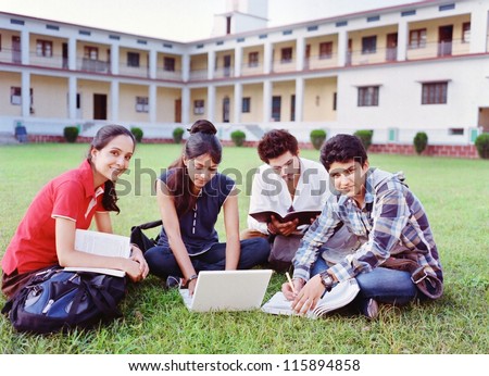 Group of Indian / Asian college students studying over the grass in the campus.